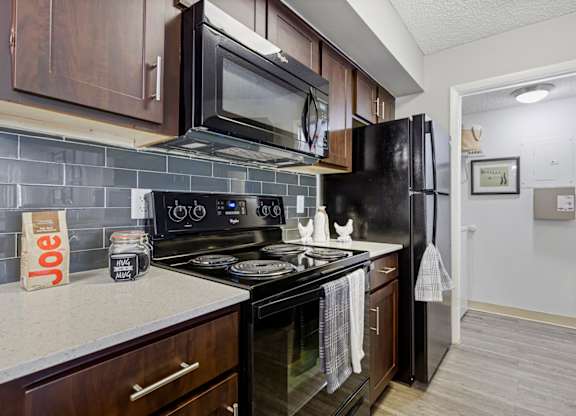 A kitchen with black appliances and brown cabinets