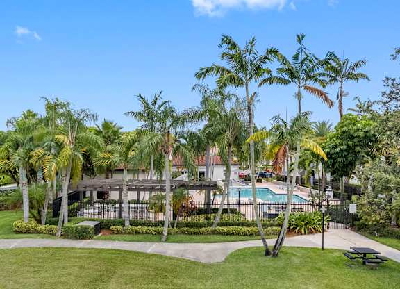 A swimming pool surrounded by palm trees and the resident clubhouse