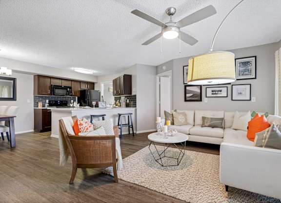 A living room hardwood-style flooring and a ceiling fan