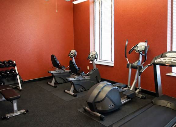 A gym with orange walls and a variety of exercise equipment.