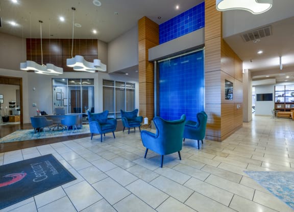 a lobby with blue chairs and a blue waterfall in the center
