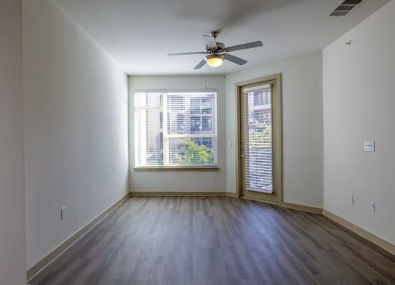 an empty living room with a ceiling fan and a window