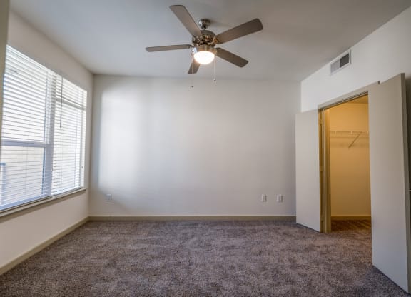 an empty room with a ceiling fan and a door to a closet