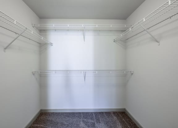 a walk in closet in a white room with a window