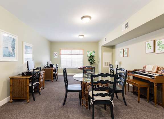 A room with a desk, chairs, and a computer.