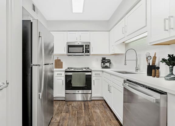 a kitchen with white cabinetry and stainless steel appliances at Caveness Farms Apartments, Wake Forest 
