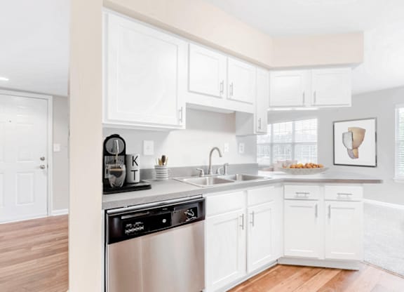 a kitchen with white cabinets and a stainless steel dishwasher at Caveness Farms Apartments, North Carolina 