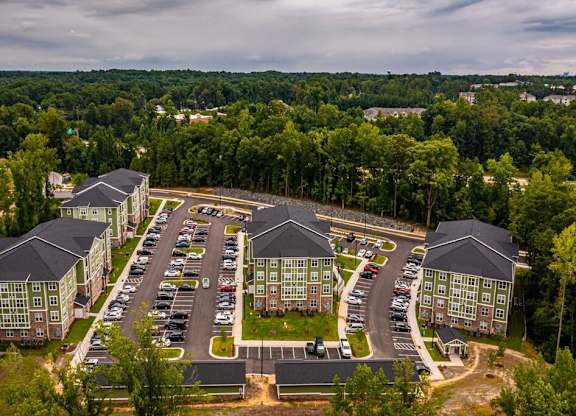 An aerial view of a parking lot surrounded by buildings and trees. at Foxwood Apartments, Raleigh-Durham