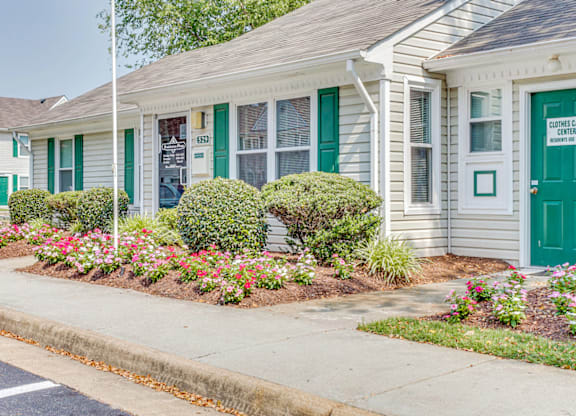 a white house with green shutters and a flower garden in front of it
