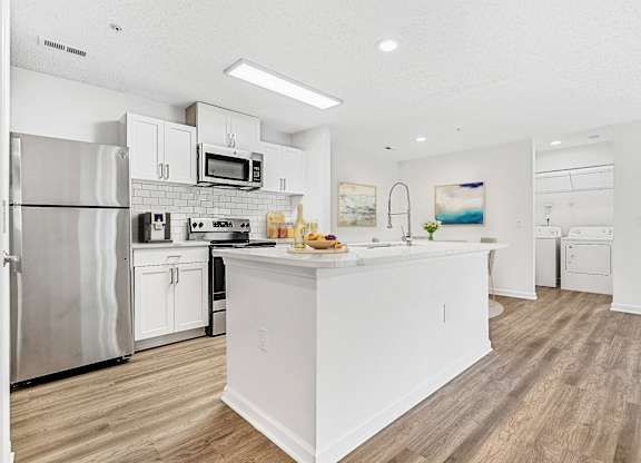 A modern kitchen with white appliances and a wooden floor. at The Grayson Apartment Homes, Charlotte