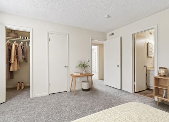 a bedroom with three doors and a table with a plant on it at Eastchester Ridge Apartments, North Carolina