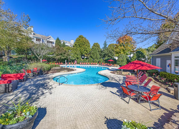 a pool with lounge chairs and umbrellas at the enclave at woodbridge apartments in sugar