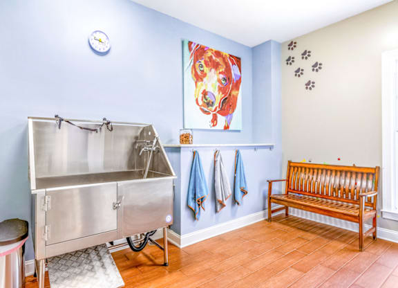 a stainless steel sink and bench in a laundry room with a painting of a dog on the