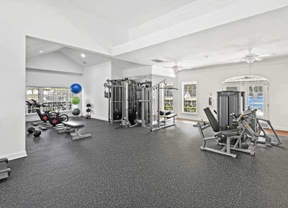 A spacious gym with a variety of equipment including a treadmill, weights, and a bench press.