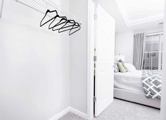A white bedroom with a bed and a white wall.