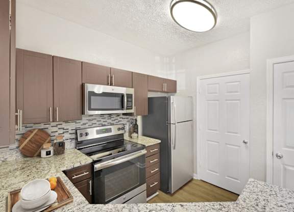 A kitchen with a refrigerator, oven, and microwave.