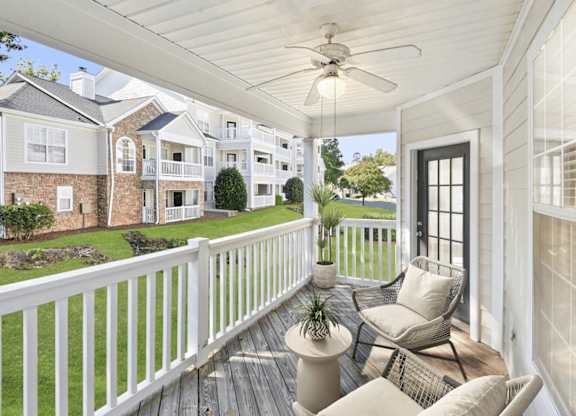 A white porch with a ceiling fan and a chair.