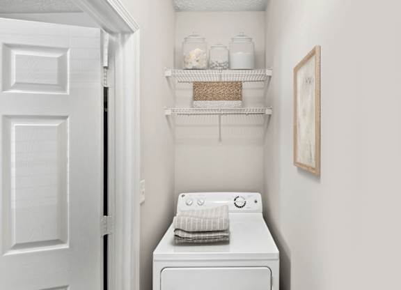 A white washing machine sits in a small laundry room.