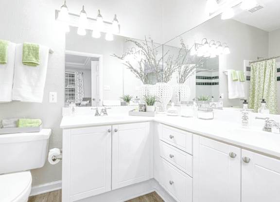 A white bathroom with a toilet, sink, and mirror.