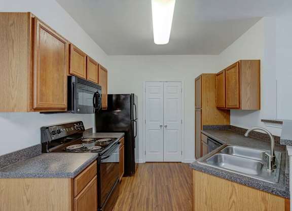 A kitchen with black appliances and wooden cabinets at Ethan Pointe Apartments, Greensboro