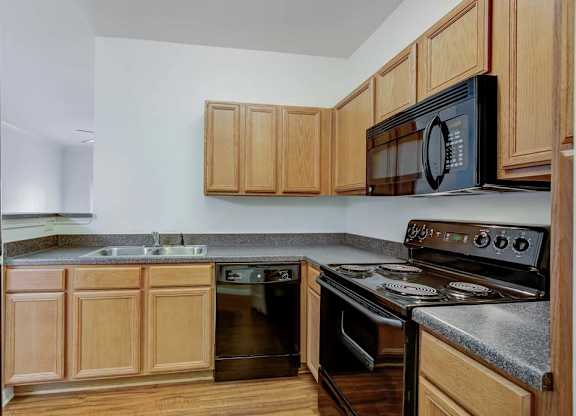 A kitchen with wooden cabinets and a black refrigerator at Ethan Pointe Apartments, Greensboro, NC