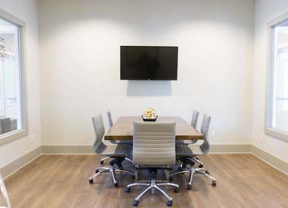 A conference room with a table, chairs, and a television mounted on the wall at Foxwood Apartments, Raleigh-Durham, 27616
