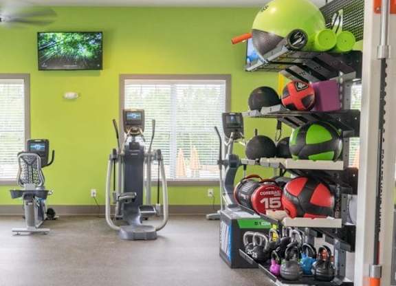 A gym with a green wall and exercise equipment at Foxwood Apartments, North Carolina, 27616