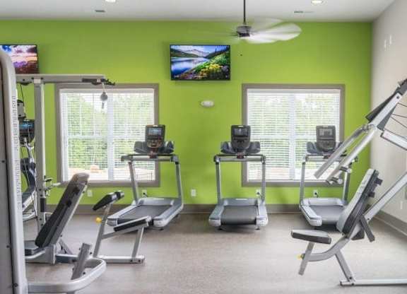 A gym with treadmills, elliptical machines, and a television at Foxwood Apartments, North Carolina