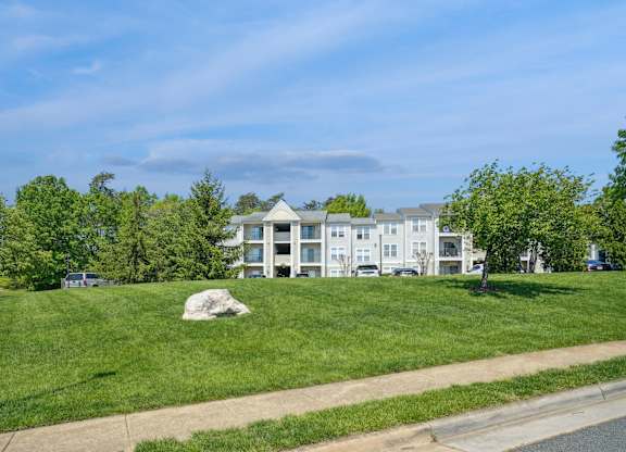 A grassy area with a building in the background and a lamp post on the left.
