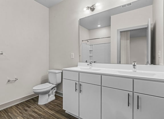 A white bathroom with a toilet, sink, and mirror at Litchford 315 Apartments, Raleigh, North Carolina
