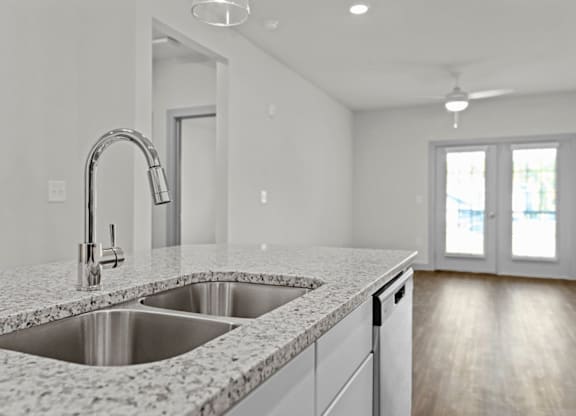 A modern kitchen with a granite countertop and stainless steel sink at Litchford 315 Apartments, North Carolina, 27615