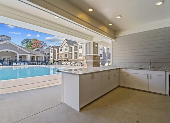 A large, empty room with a pool table and a view of a residential area outside at Litchford 315 Apartments, Raleigh, 27615