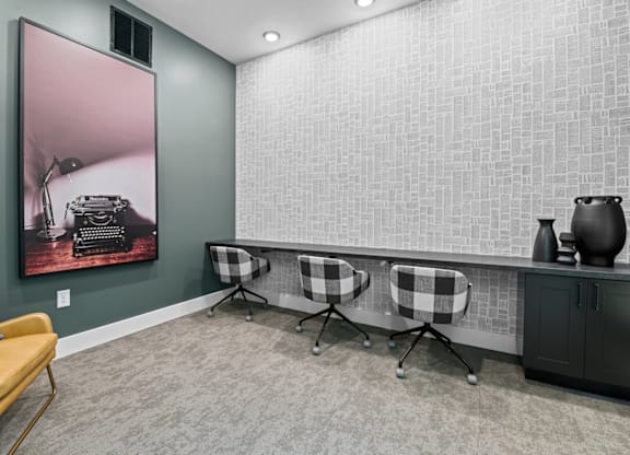 A room with a yellow chair, a painting of a camera, and a black and white checkered table at Litchford 315 Apartments, North Carolina, 27615