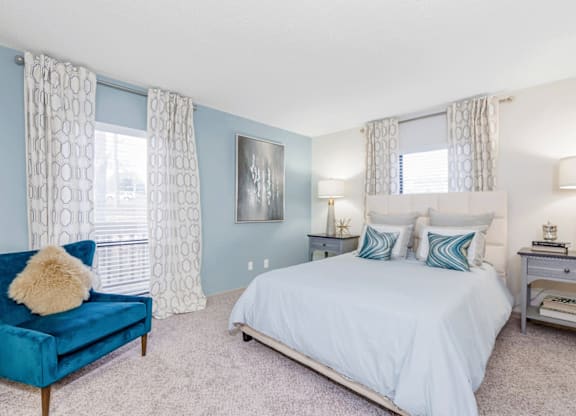 A bedroom with a blue couch and a white bed at Madison Southpark Apartment Homes, Charlotte, 28226