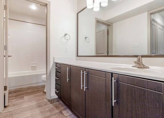 A bathroom with a white tub and brown cabinets at Madison Southpark Apartment Homes, Charlotte, 28226