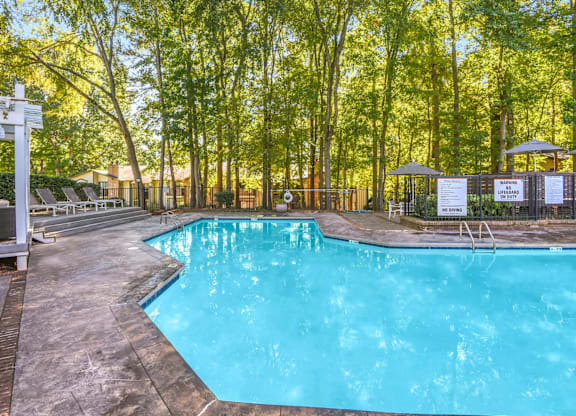 A pool surrounded by trees and a white pergola at Madison Southpark Apartment Homes, North Carolina, 28226