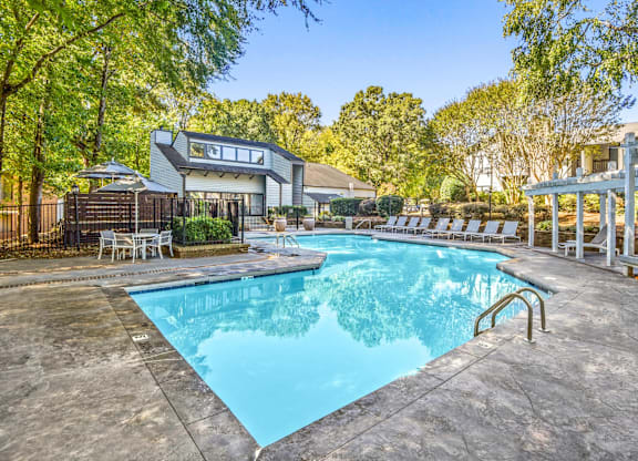 A swimming pool surrounded by trees and a house at Madison Southpark Apartment Homes, North Carolina
