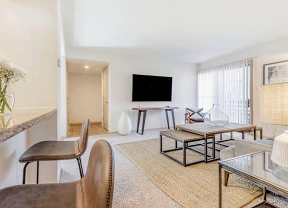 A living room with a flat screen TV, a glass coffee table, and a brown leather chair at Madison Southpark Apartment Homes, North Carolina, 28226