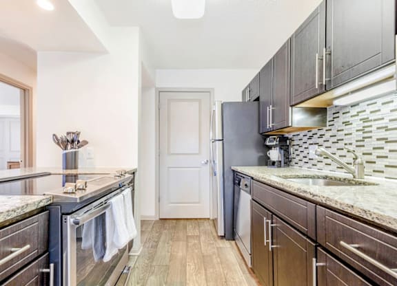 A kitchen with dark wood cabinets and granite countertops at Madison Southpark Apartment Homes, Charlotte, NC