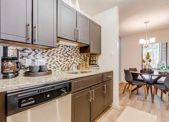 A kitchen with a black dishwasher and brown cabinets at Madison Southpark Apartment Homes, Charlotte, NC