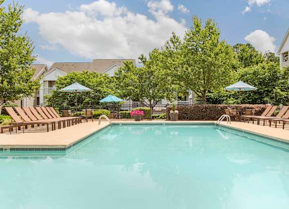 Swimming Pool and Sun Deck with Lounge Chairs with Trees and Building Exteriors in the Background at The Grayson Apartment Homes, Charlotte, North Carolina