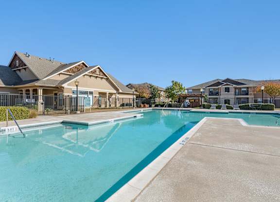 Swimming pool with large tanning deck, lounge chairs, pergola and native surrounding landscape