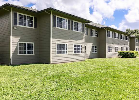 A row of apartments with grass in front.