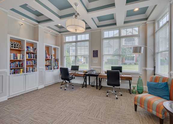 A room with a desk, chairs, and bookshelves.