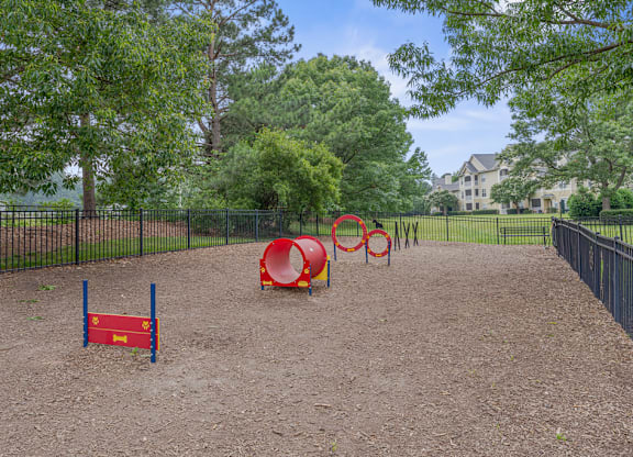 A playground with a red tunnel and a blue and red climbing frame.