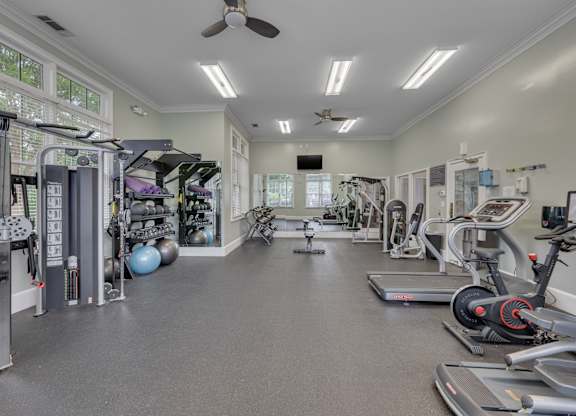 A spacious gym with a variety of equipment and a ceiling fan.