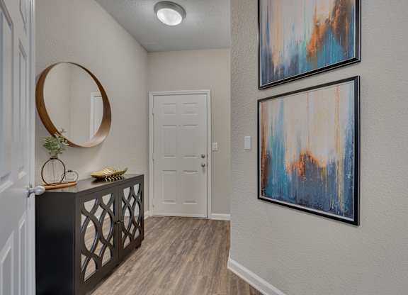 A hallway with a black railing and two framed artworks on the wall.