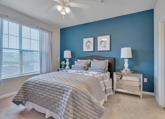 A bedroom with a bed, nightstands, and a ceiling fan.