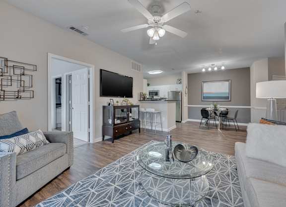 A modern living room with a glass coffee table in the center.