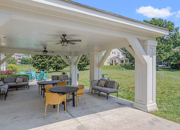 A covered patio with a table and chairs.